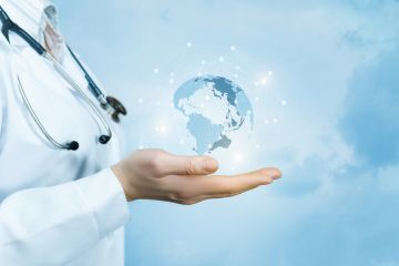 Doctor holds globe, illustrating THE University Impact Forum: Improving Health Outcomes, Transforming Lives