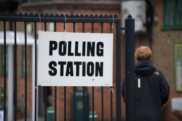 Someone walks into a polling station - helpfully there is a big sign saying 'polling station' Someone walks into a polling station