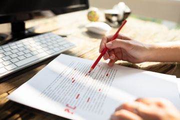 Person marking an error on a page with red marker Person marking an error on a page with red marker