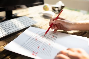 Person marking an error on a page with red marker