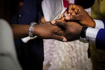 A groom puts a ring on his bride's finger