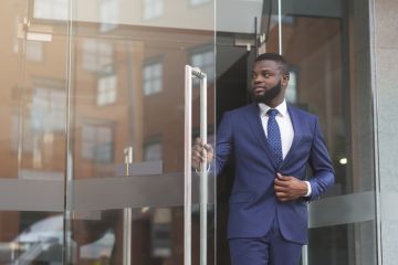Businessman in formal suit walking out of modern office
