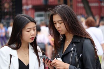 Two girls look at smartphone standing on Manezh square in the Moscow Two girls look at smartphone standing on Manezh square in the Moscow