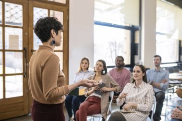 A woman giving a university lecture to several students 