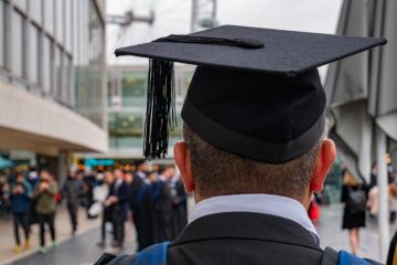  graduated student looking back to his colleagues and friends in University campus in London