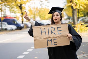 Graduate student standing with hire me placard