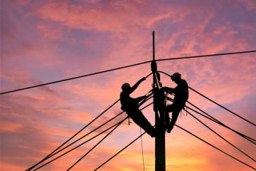Electrician climbing electric power pole to repair damaged power cable line