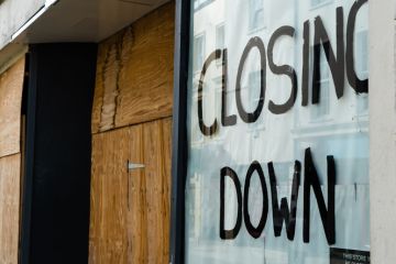 Closing down sign in a boarded-up shop window