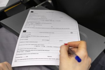 A woman on board a plane fills out a passenger information form. A woman on board a plane fills out a passenger information form.