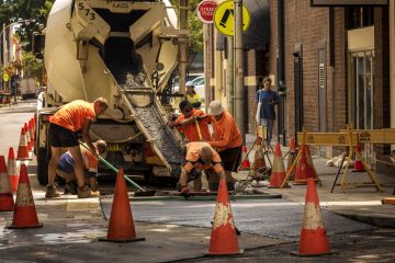 Group of men in orange dress pouring concrete from a truck