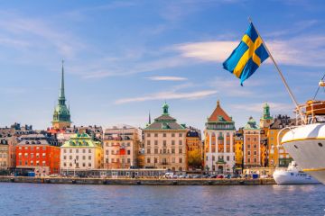 The Stockholm skyline with a flag of Sweden perched on a boat