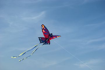 Children's butterfly kite flying on blue sky background