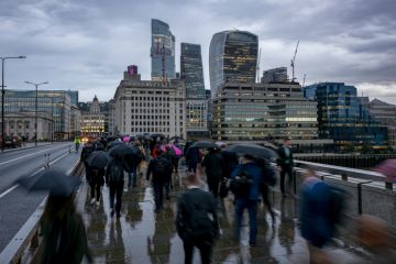 People cross a London bridge in the rain People cross a London bridge in the rain