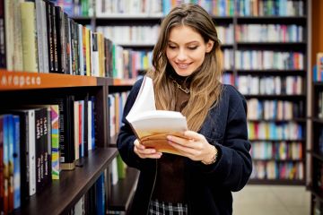 A stock image of a woman reading a book in a library 