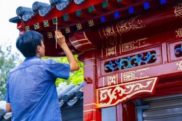 Chinese Man Painting Facade of SOuvenir Store near the Yonghegong Lama Temple