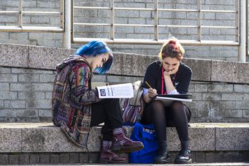 Two young female students studying outdoors. Two young female students studying outdoors.