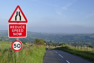 Sign on a road says 'reduce speed now'