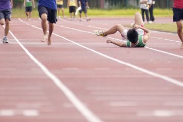 A runner falls over in a race on a track