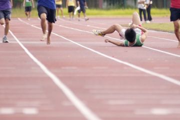 A runner falls over in a race on a track A runner falls over in a race on a track