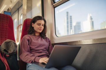 Student commuter on laptop on train Student commuter on laptop on train