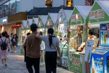 A couple walks past ice cream stalls during an evening festival in Suzhou, China. A couple walks past ice cream stalls during an evening festival in Suzhou, China.