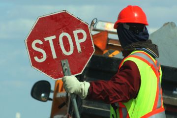 Worker Holding Stop Sign Against Vehicle On Road Worker Holding Stop Sign Against Vehicle On Road