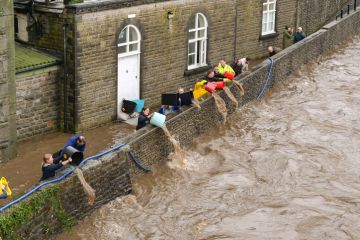 People tipping floodwater out of the basement level of Pontypridd town museum in south Wales