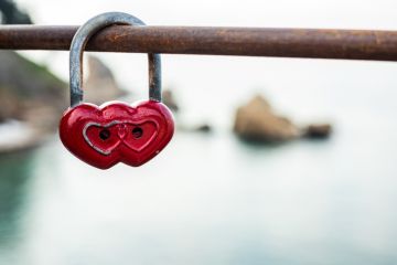 Red double heart padlock hangs on bridge