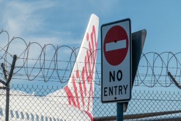 A Virgin Australia Boeing B737-8FE plane parked behind a security fence A Virgin Australia Boeing B737-8FE plane parked behind a security fence