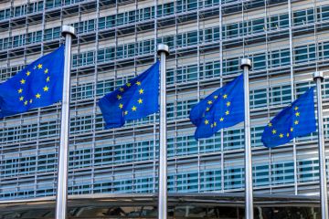 Four European flags fluttering against the headquarters of the European Commission