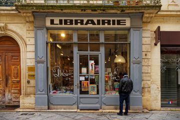 1 person is looking into an old bookstore 1 person is looking into an old bookstore