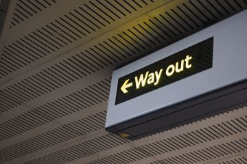 Illuminated Way Out Sign With Arrow In Modern Indoor Public Transportation Area