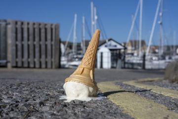 A dropped ice cream cone melting on a sunny road