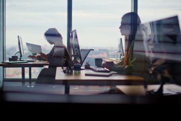 Busy corporate office silhouettes at cityscape window