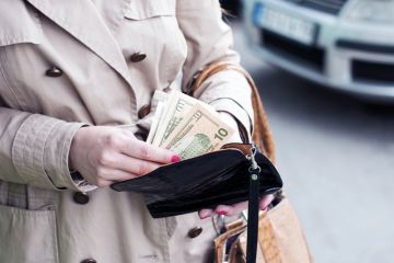 A woman puts some dollars into her purse A woman puts some dollars into her purse