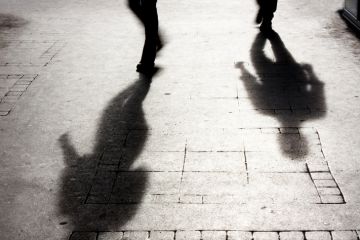 Shadow of two people on pattered sidewalk in black and white