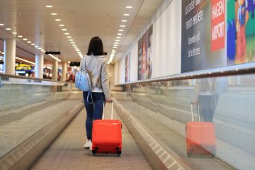 One girl with red suitcase in airport