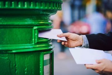  man posting mail into a postbox in the city