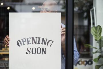 Man putting “store opening” sign in shop window Man putting “store opening” sign in shop window