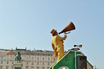 Clown playing circus street show and talking into the loudspeaker during the Carnival at the Milan Duomo square