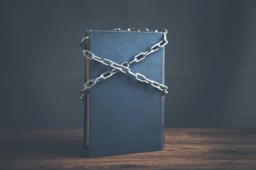 Blue book chained with lock on a wooden table