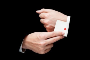 A conjuror pulls the ace of hearts out of his sleeve card trick sleight of hand ace up the sleeve illusion