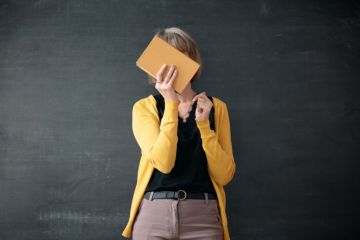 Teacher hiding face with a book hiding face