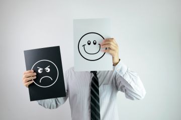 Man holding smiling and frowning faces