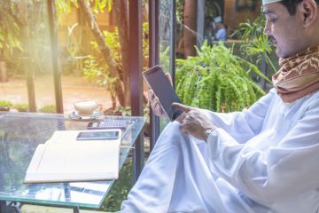 A Pakistani man works on a phone in a coffee shop