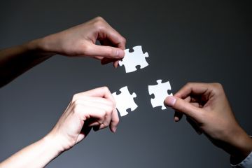 People holding three jigsaw pieces, symbolising the Adelaide university merger