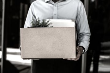 A man carries a box of his belongings, illustrating redundancy A man carries a box of his belongings, illustrating redundancy