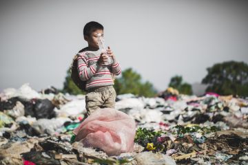 A poor boy finds a plastic bottle in a landfill site A poor boy finds a plastic bottle in a landfill site
