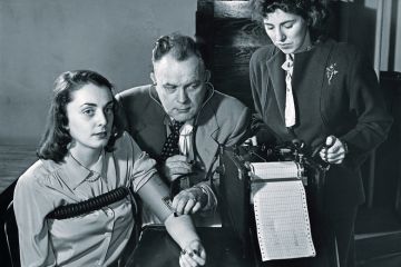 Two researchers conducting a lie detector test on a young woman Two researchers conducting a lie detector test on a young woman