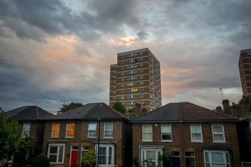 London. UK-05.17.2022. Semi detached houses and a local council social housing block of flats in a typical suburb of the capital with cloudy sunset sky.